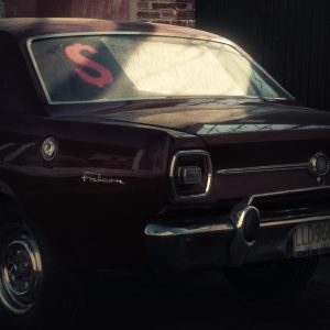 Rear view of a vintage maroon car with a for sale sign, parked outdoors.