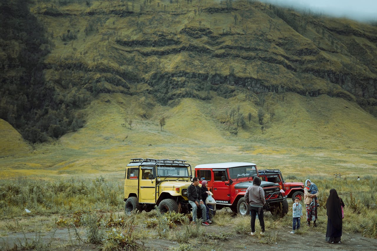 People enjoying adventure near colorful jeeps in a mountainous landscape.